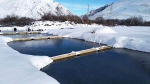 A snow-covered outdoor area with a rectangular pool and a concrete structure. - Come &Rest (Kazbegi)