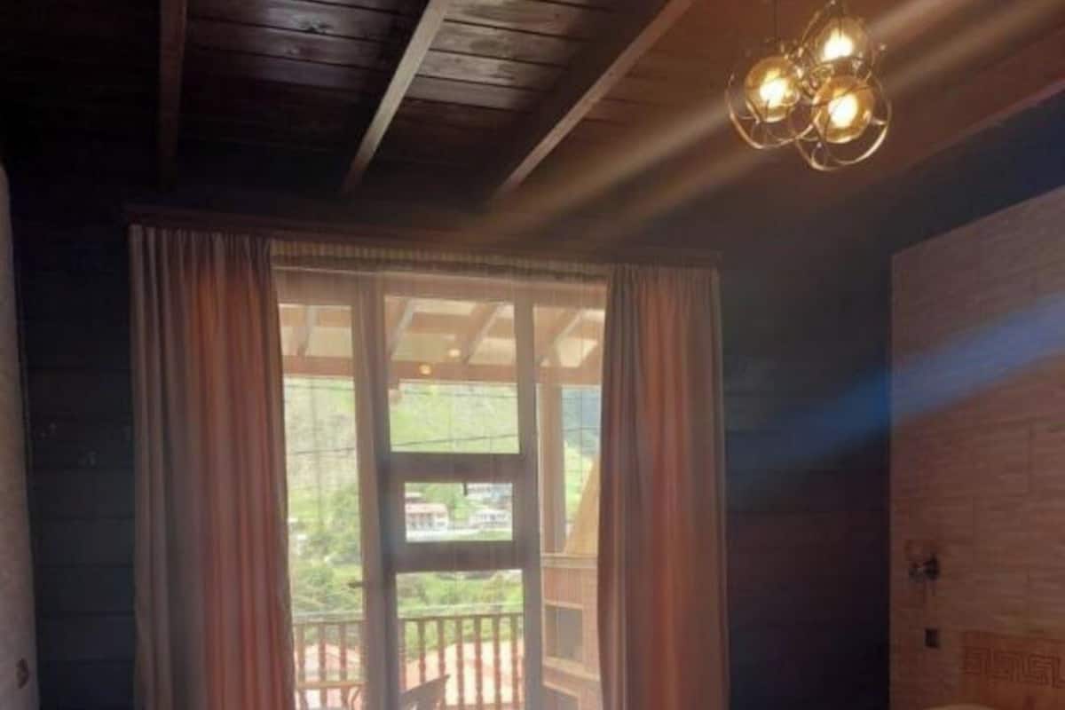A bedroom with a wooden ceiling, a bed with pillows, a nightstand, and a sliding glass door leading to an outdoor area.