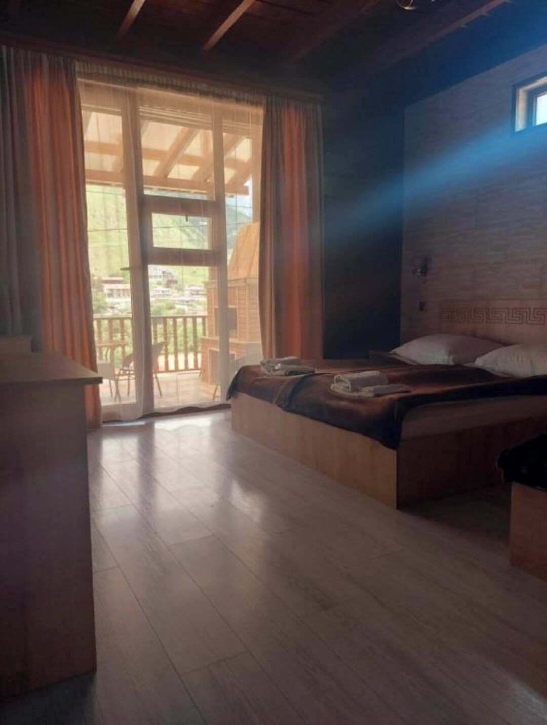 Un dormitorio con cama, escritorio y vistas al exterior a través de una puerta de vidrio.