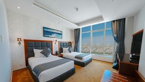 Une chambre d’hôtel avec deux lits, une télévision et une grande fenêtre donnant sur la ville.