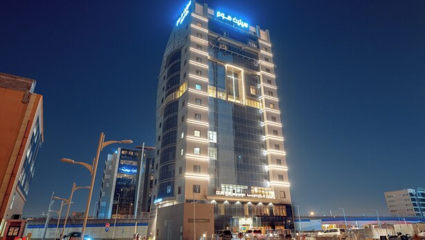 Un hôtel moderne, reconnaissable à son grand panneau « Plaza », à ses nombreux étages et à sa façade bien éclairée.