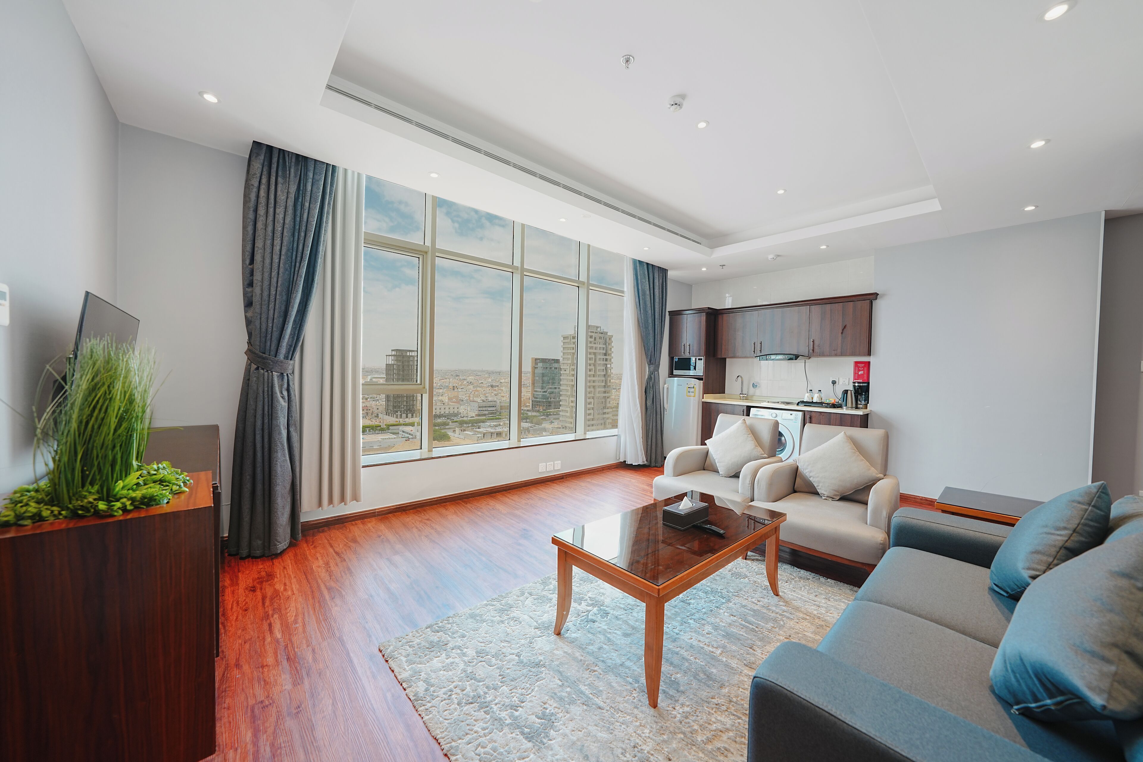Un salon moderne avec un canapé, une table basse et une vue sur la ville grâce à de grandes fenêtres.