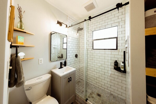 A modern bathroom with a toilet, sink, and glass shower enclosure. - Gorgeous Modern Getaway w/ Peloton & Dual Monitors WFH set-up (Seattle)