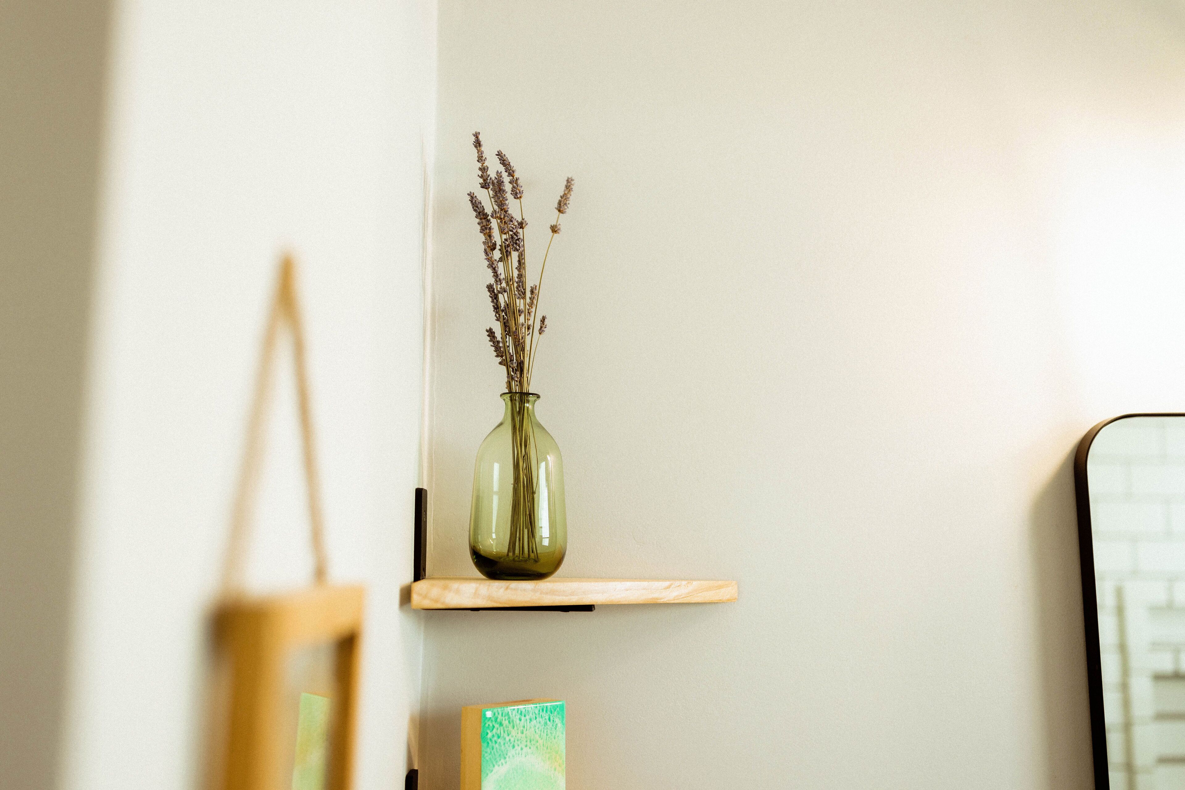 A wall-mounted shelf with a vase of dried flowers.