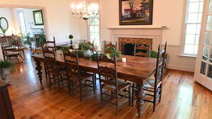 A dining room with a wooden table, chairs, and a fireplace.
