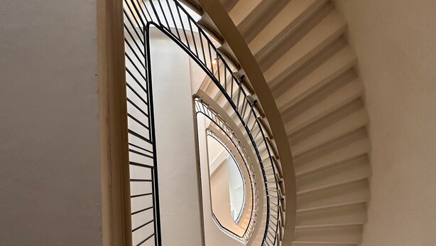A spiral staircase with a modern design, featuring a central column and a handrail on the outer side. - The Monache Loggia (Gap)