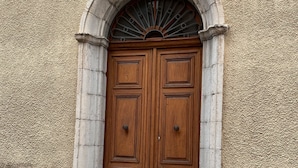 A double wooden door with a stone archway and a decorative fanlight above it. - The Monache Loggia (Gap)