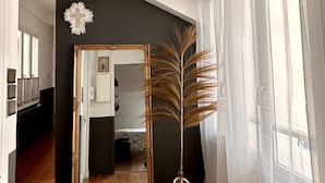 A hallway with a large mirror, a decorative plant, and a hanging light fixture. - The Monache Loggia (Gap)