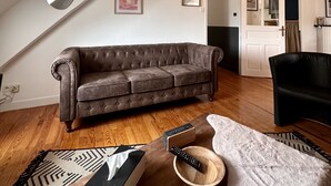 A loft-style living room with a brown leather couch, wooden flooring, and a high ceiling. - The Monache Loggia (Gap)