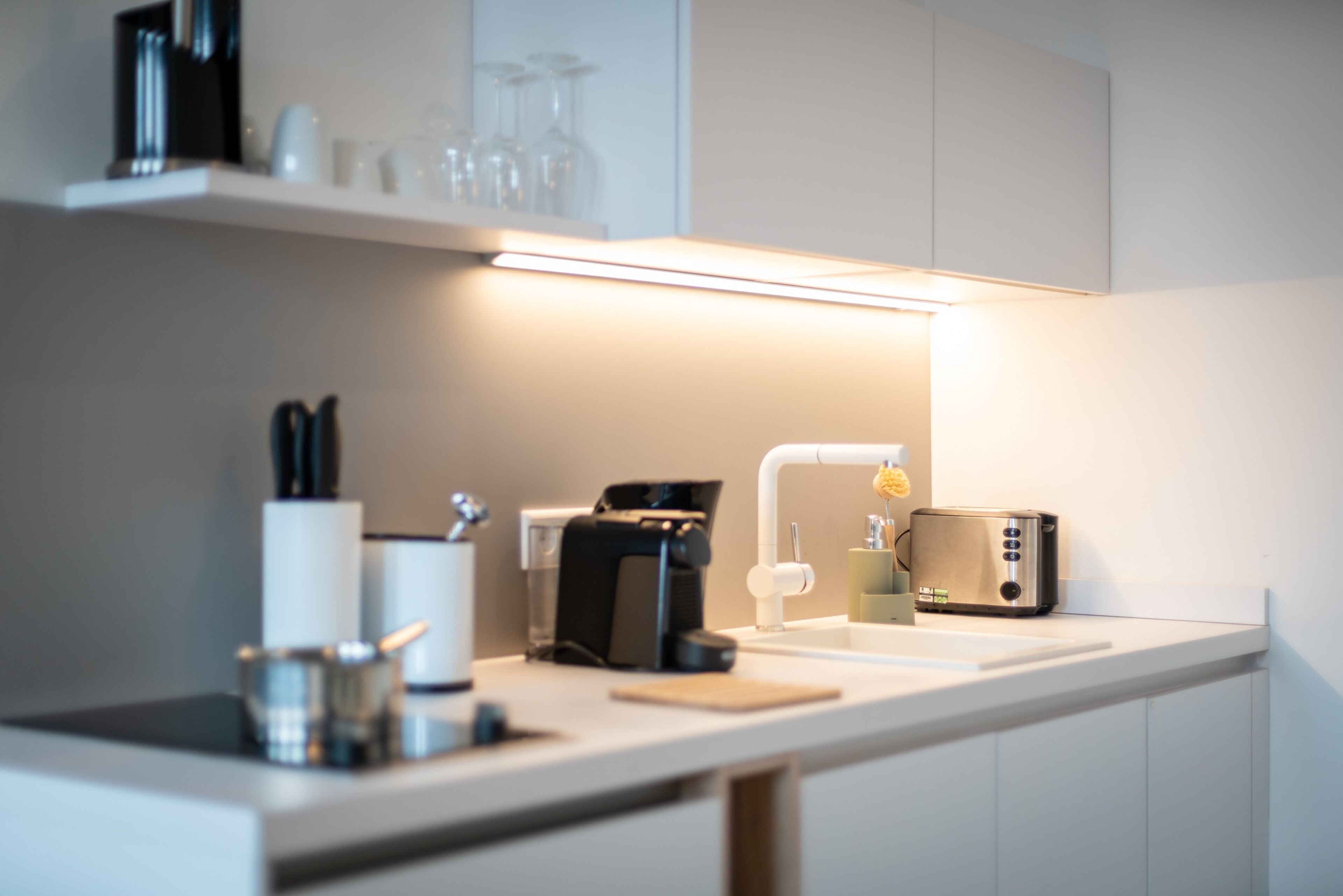 A modern kitchen with a countertop, a coffee maker, a toaster, and a sink.