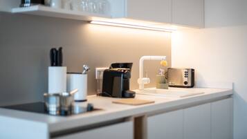 A modern kitchen with a countertop, a coffee maker, a toaster, and a sink.