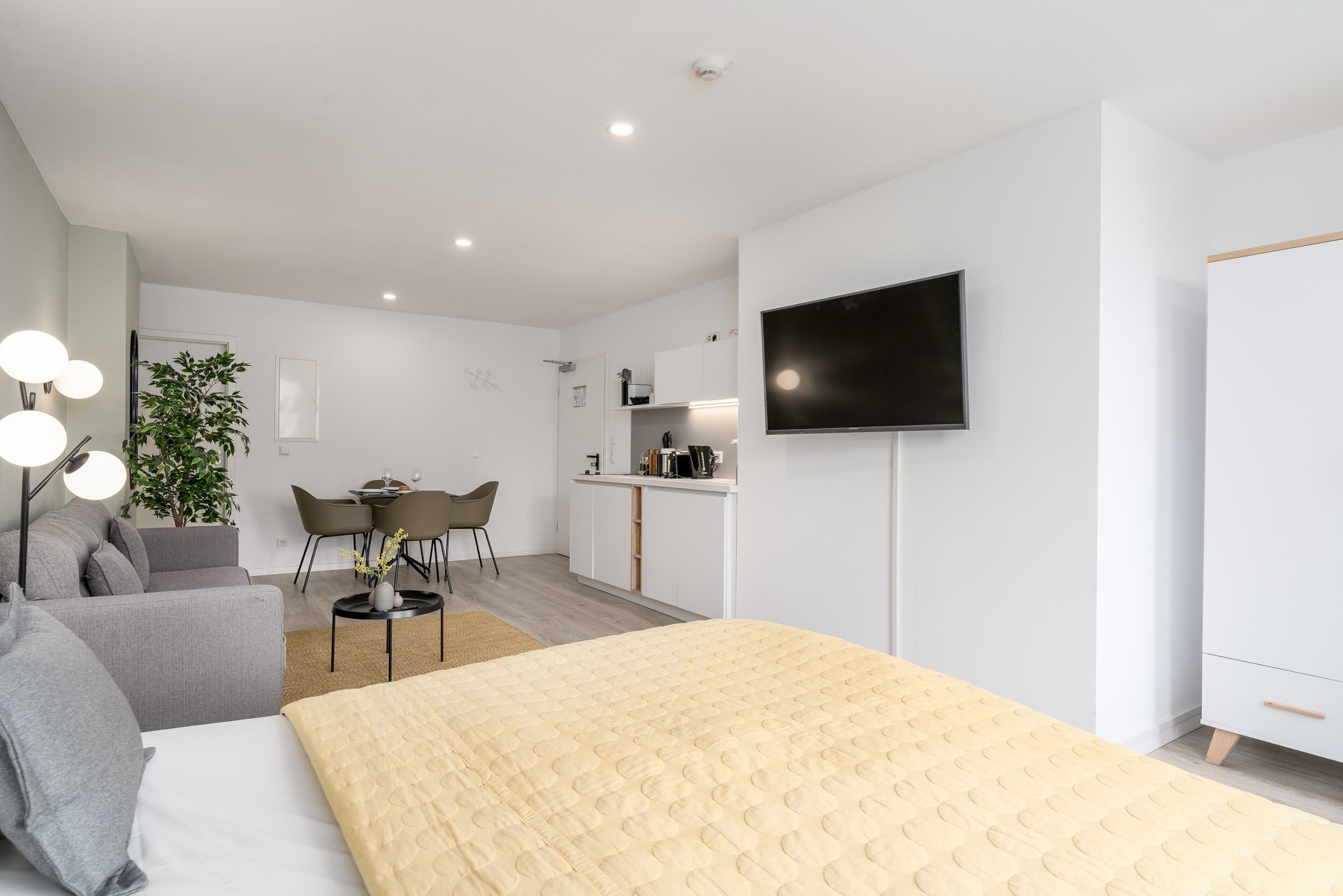 Una habitación de hotel moderna con cama, televisión, escritorio y zona de comedor.