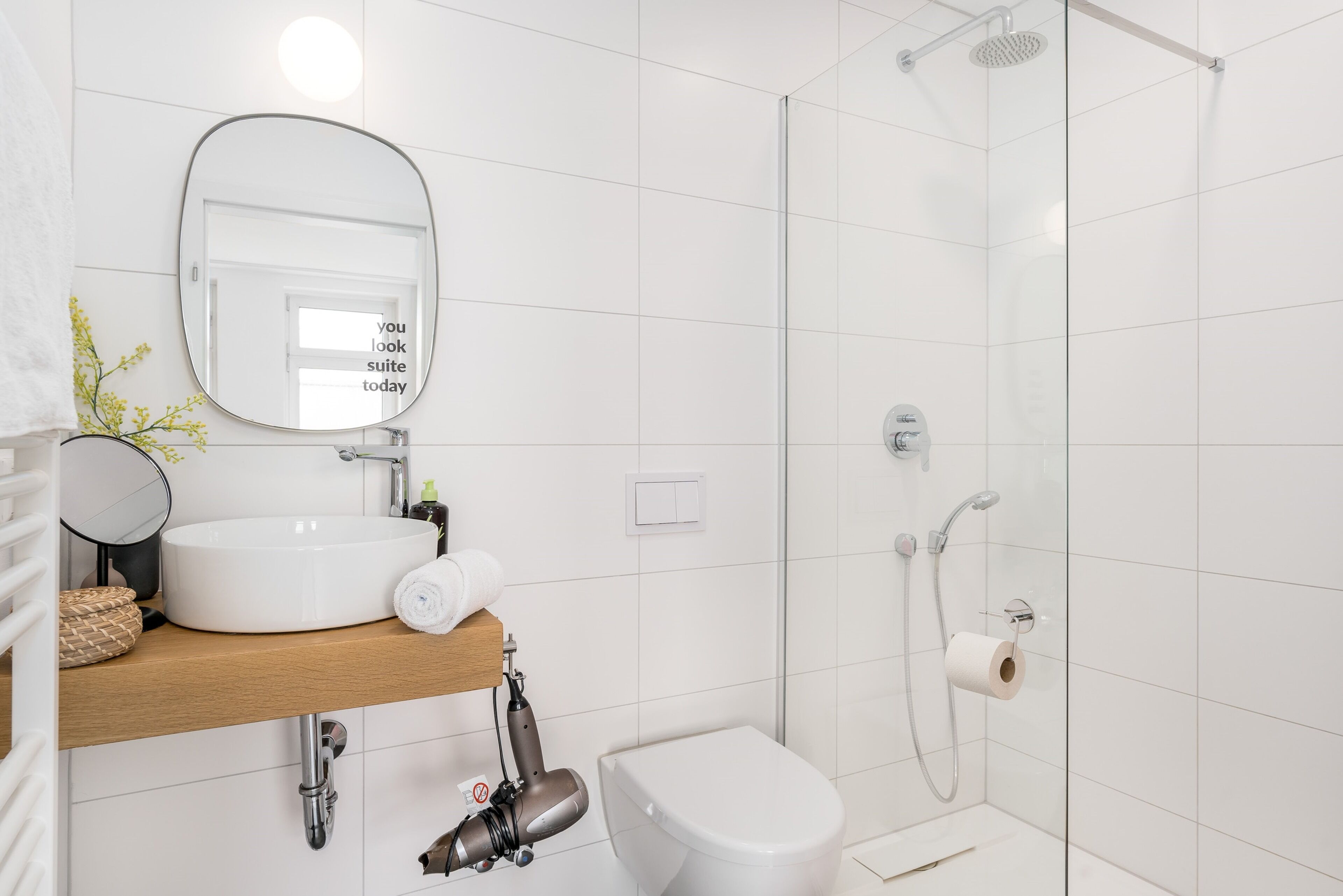 Een moderne badkamer met een witte wastafel, spiegel en toilet.