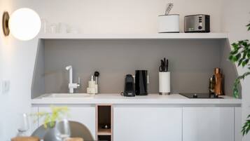 A modern kitchen with white cabinetry, a built-in coffee machine, and a small plant on the counter.