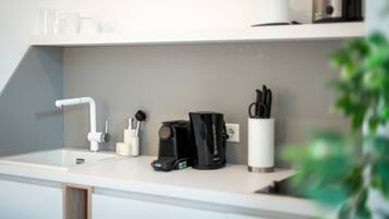 A modern kitchen with a white countertop, a coffee maker, a toaster, and a sink.
