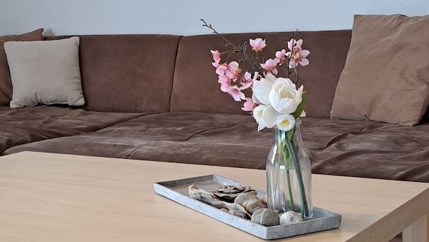 Une table basse en bois, ornée d’un vase de fleurs et d’un plateau contenant divers objets décoratifs.