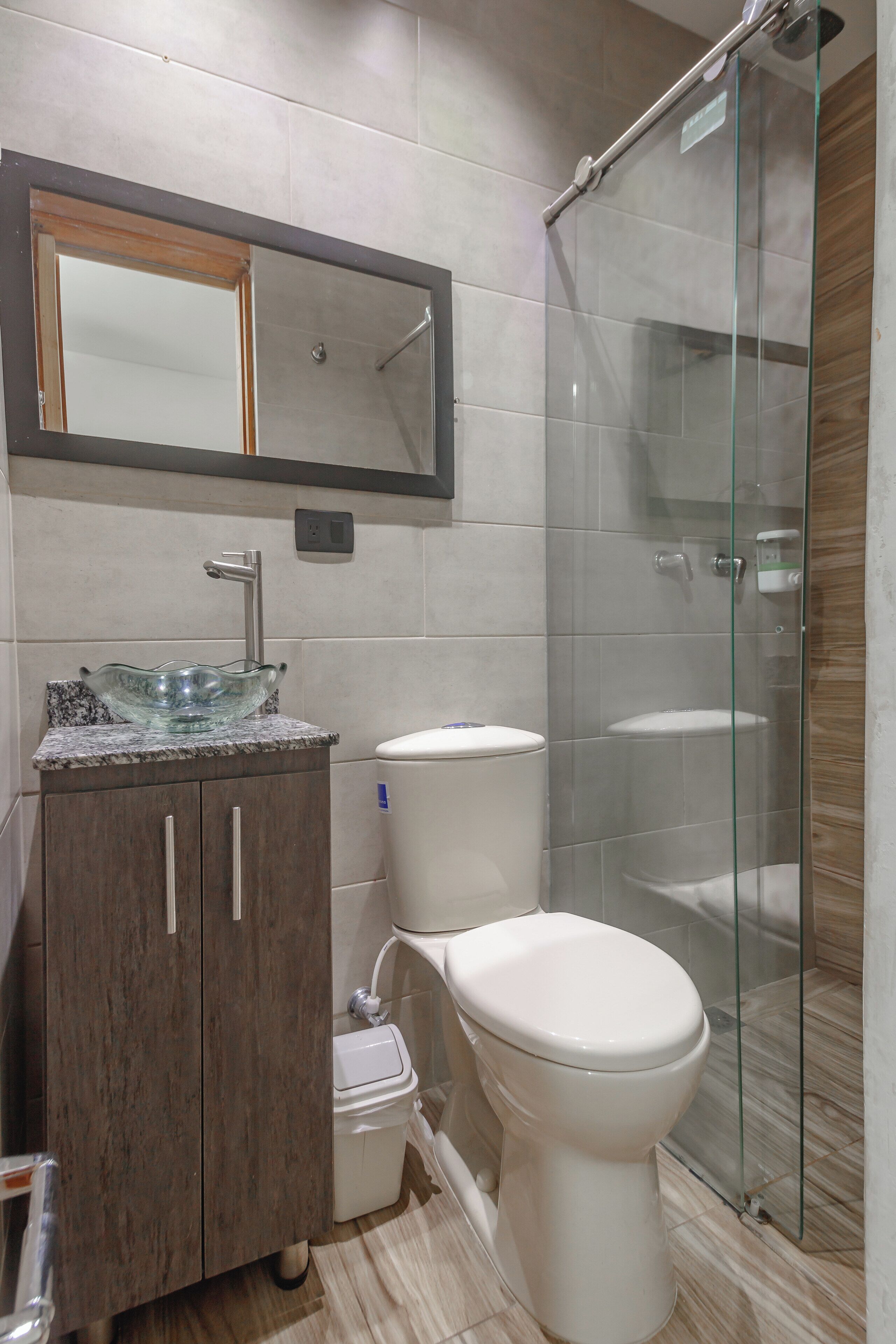 A modern bathroom with a glass shower enclosure, a marble sink, and a white toilet.