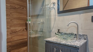 A modern bathroom with a glass shower enclosure, a granite countertop sink, and a wooden vanity. - Machu Picchu Medellin (Medellín)