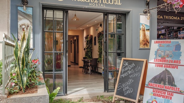 A hostel entrance with a sign reading "Machu Picchu Hostel," a chalkboard with services, and a signboard advertising laundry and tours. - Machu Picchu Medellin (Medellín)