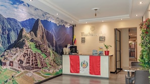 A reception desk with a mural of Machu Picchu, a flag, and a coat of arms. - Machu Picchu Medellin (Medellín)