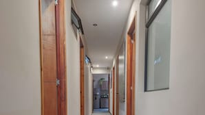 A long, narrow hallway with wooden doors and a light-colored floor. - Machu Picchu Medellin (Medellín)