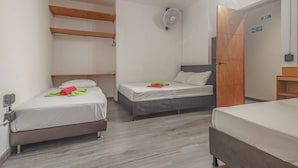 A hotel room with two single beds, a wooden ceiling, a standing fan, and a door with an emergency exit sign. - Machu Picchu Medellin (Medellín)