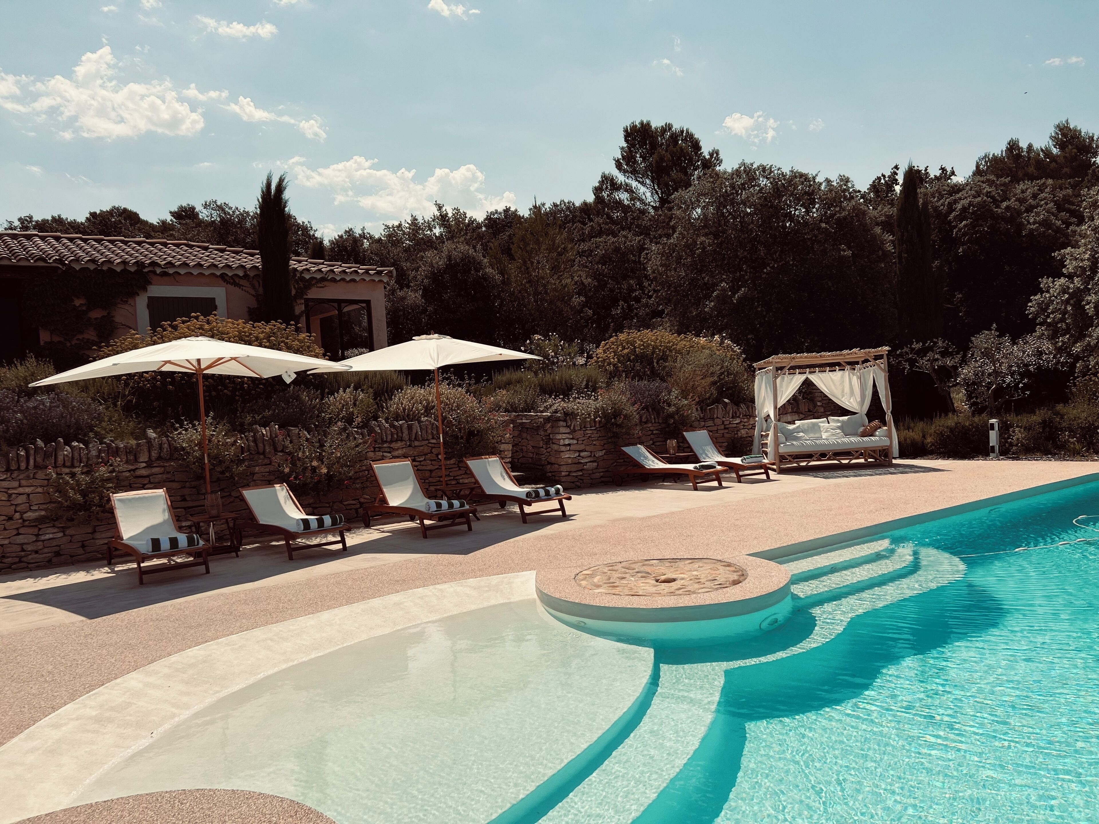 A poolside area with lounge chairs, a canopy, and a bed with a canopy.