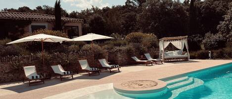 A poolside area with lounge chairs, a canopy, and a bed with a canopy.