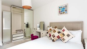 Ett hotellrum med en säng, ett skrivbord, en garderob och en spegel.