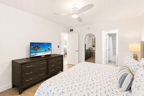 A bedroom with a bed, a dresser, a television, and a ceiling fan.