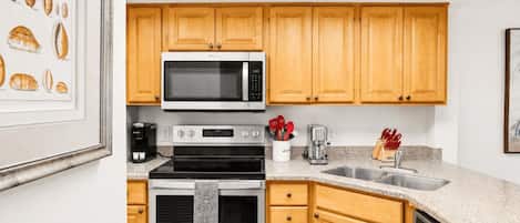 Una cocina con armarios de madera, microondas, estufa y lavavajillas.