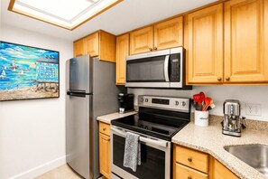 A kitchen with wooden cabinets, a stainless steel refrigerator, a microwave, an oven, and a coffee maker. - Park Shore Resort 2nd Floor BLDG J #254 (Park Shore Resort)