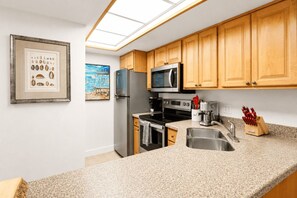 A kitchen with wooden cabinets, stainless steel appliances, a granite countertop, and a skylight. - Park Shore Resort 2nd Floor BLDG J #254 (Park Shore Resort)