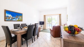 Uma sala de jantar com uma mesa de madeira, cadeiras pretas, uma televisão e uma cesta de frutas.