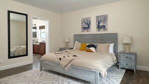 A bedroom with a bed, two nightstands, a mirror, and two wall art pieces. - Mountain Paradise - Pickleball / Hot Tub / Games (Jewett)