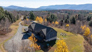 A large house with a dark roof, a porch, and a driveway leading to a parking area. - Mountain Paradise - Pickleball / Hot Tub / Games (Jewett)
