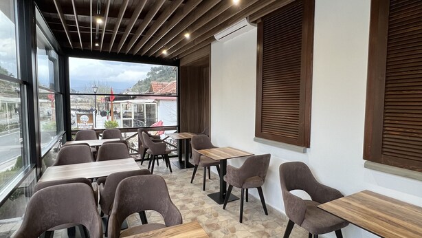 Ein Restaurantinneres mit Holzbalkendecke, steinbelagtem Boden und modernen Möbeln.
