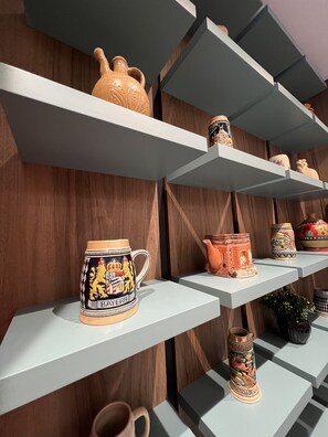 A display of various ceramic mugs and vases on shelves against a wooden wall. - Bujtina Apsus (Berat)