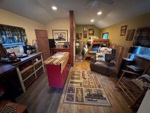 Una stanza accogliente con un letto a castello, una scrivania con un computer, una macchina per il caffè e un tappeto con decorazioni varie.