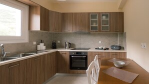 Een moderne keuken met houten kastjes, een inbouwoven, een spoelbak en een eethoek met een tafel en stoelen.