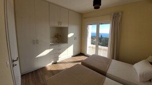 Een slaapkamer met een grote kast, een balkon met uitzicht over de stad, en twee bedden.