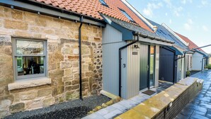 Un bâtiment en pierre avec un toit recouvert de tuiles, une fenêtre et une porte.