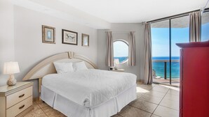 Un dormitorio con cama, mesita de noche y vista al océano.