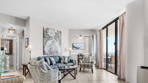 Un salón amplio con un sofá, sillones, una mesa de centro y un cuadro grande.