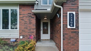 A residential house with a brick facade, a white front door, and a garage door. - Hot Tub - Pool Table - Fire Pit - Family Friendly!  Hosted by Homes by CNJ. (Wichita)