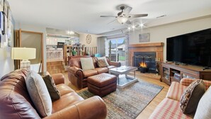 A spacious living room with a fireplace, leather sofas, a television, and a ceiling fan. - Hot Tub - Pool Table - Fire Pit - Family Friendly!  Hosted by Homes by CNJ. (Wichita)
