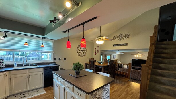 A modern kitchen with a central island, pendant lights, and a dining area with wooden furniture. - Hot Tub - Pool Table - Fire Pit - Family Friendly!  Hosted by Homes by CNJ. (Wichita)