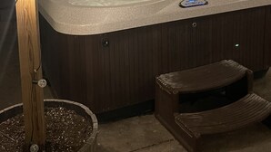 A hot tub with a control panel, surrounded by wooden posts and string lights. - Hot Tub - Pool Table - Fire Pit - Family Friendly!  Hosted by Homes by CNJ. (Wichita)
