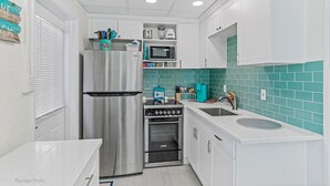 A compact kitchen with a stainless steel refrigerator, a microwave, and an oven. - Private cottage | 50 steps to BEACH! (Indian Rocks Beach)