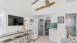 A compact kitchen with a refrigerator, microwave, and stove. There is a dining area with a table and chairs. - Private cottage | 50 steps to BEACH! (Indian Rocks Beach)